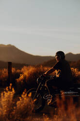 Motorradfahrer fährt durch die Landschaft von Kennedy Meadows, Kalifornien, USA - ISF21785