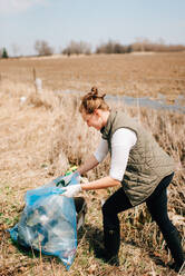 Frau beim Aufsammeln von Müll auf einem Feld, Georgetown, Kanada - ISF21809