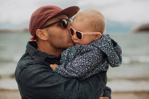 Vater küsst Baby am Strand, lizenzfreies Stockfoto