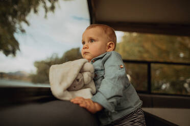 Baby looking out window of motorhome, Wanaka, Taranaki, New Zealand - ISF21828