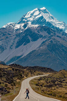 Wanderer beim Überqueren der Straße, die zu den Bergen führt, Wanaka, Taranaki, Neuseeland - ISF21841