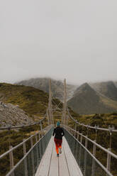 Hiker crossing suspension bridge, Wanaka, Taranaki, New Zealand - ISF21866