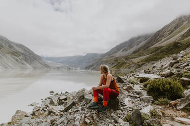 Woman enjoying scenic view by lake, Wanaka, Taranaki, New Zealand - ISF21874