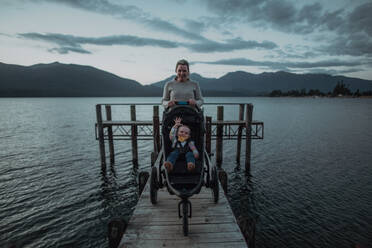 Mother with baby in pram on bridge by seaside, Te Anau, Southland, New Zealand - ISF21882