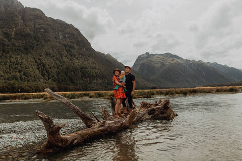 Eltern und Baby auf umgestürztem Baum im See, Queenstown, Canterbury, Neuseeland, lizenzfreies Stockfoto