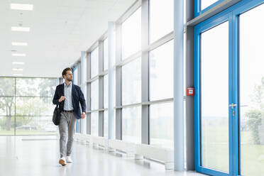 Young businessman walking in a passageway - DIGF07060