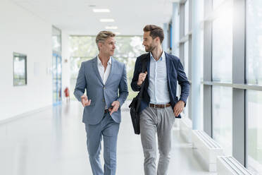 Two businessmen walking and talking in a passageway - DIGF07062