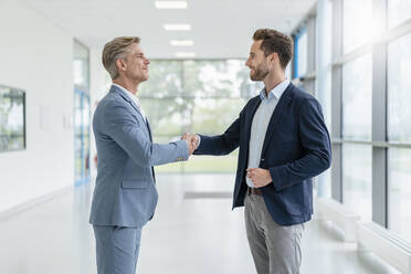 Two businessmen shaking hands in a passageway - DIGF07072