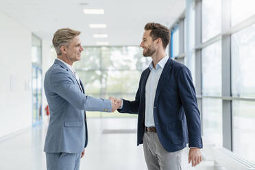 Two businessmen shaking hands in a passageway - DIGF07073