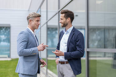 Two businessmen talking outside office building - DIGF07085