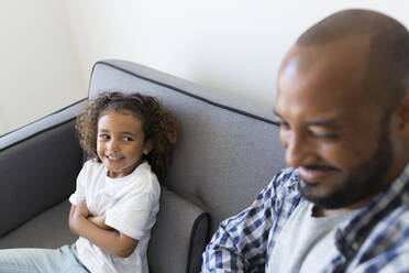 Glücklicher Vater und Tochter sitzen auf der Couch zu Hause - JPTF00190