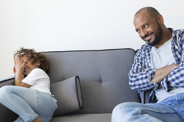 Glücklicher Vater und Tochter sitzen auf der Couch zu Hause - JPTF00191
