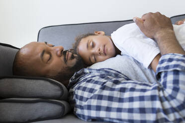Father and daughter sleeping on couch at home - JPTF00199