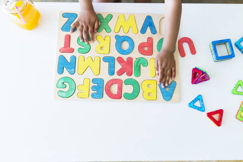 Nahaufnahme eines Mädchens, das mit einem Alphabet-Lernspiel auf einem Tisch spielt - JPTF00201