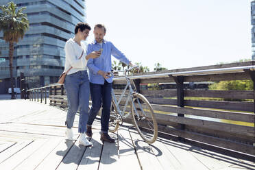 Ehepaar mit Fahrrad, Frau mit Smartphone in Barcelona - JSRF00332