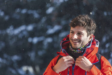 Porträt eines lächelnden Mannes im Schneefall, Saalbach Hinterglemm, Pinzgau, Österreich - MMAF01062