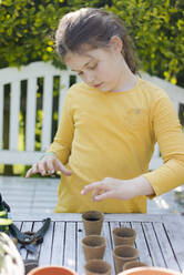 Girl with nursery pots on garden table - MOEF02265