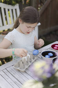 Mädchen beim Färben von Ostereiern im Garten - MOEF02296