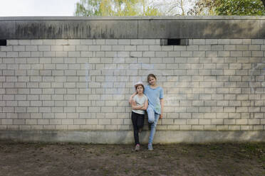 Porträt von zwei Mädchen, die an einer Backsteinmauer stehen - MOEF02307