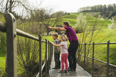 Mutter mit zwei Kindern auf einer Brücke auf dem Lande - FBAF00766