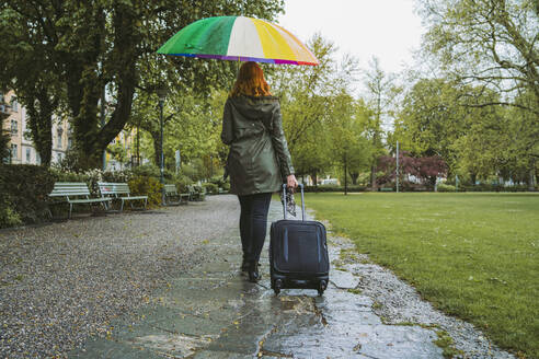 Junge Frau, die an einem regnerischen Tag im Stadtpark spazieren geht - FBAF00772