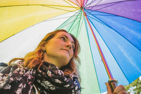Junge Frau unter buntem Regenschirm, lizenzfreies Stockfoto