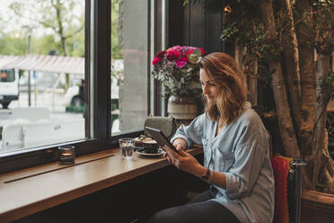 Young woman with an e-book in a cafe - FBAF00777