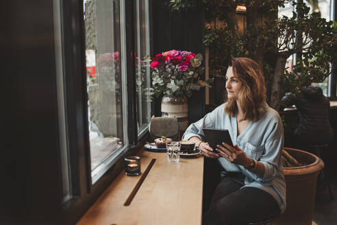 Junge Frau mit einem E-Book in einem Cafe - FBAF00778