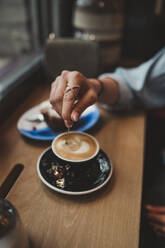 Nahaufnahme einer Frau mit einem Cappuccino in einem Cafe - FBAF00780
