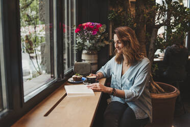 Junge Frau liest ein Buch in einem Café - FBAF00782