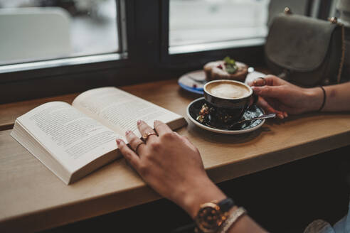 Nahaufnahme einer Frau mit einem Buch in einem Cafe - FBAF00783