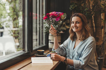 Young woman enjoying a cake in a cafe - FBAF00786