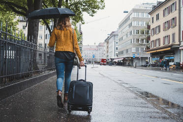 Junge Frau, die an einem regnerischen Tag in der Stadt spazieren geht, Zürich, Schweiz - FBAF00791