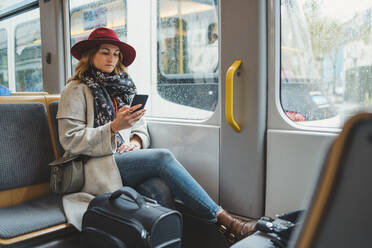 Young woman using cell phone in a tram - FBAF00792