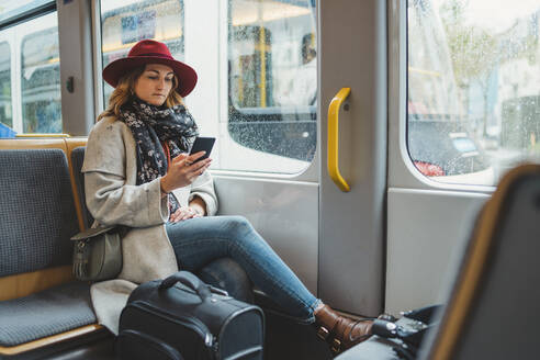 Junge Frau benutzt Mobiltelefon in einer Straßenbahn - FBAF00792