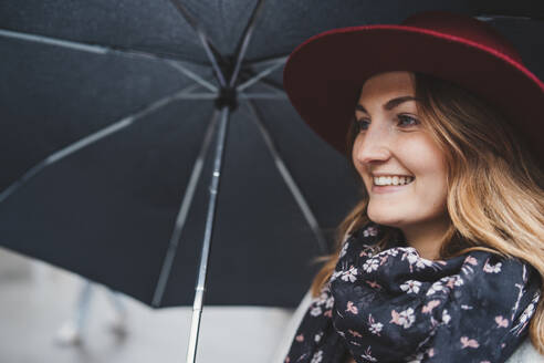 Porträt einer glücklichen jungen Frau unter einem Regenschirm - FBAF00794