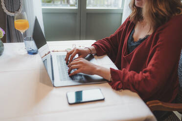 Close-up of woman using laptop on table in a cafe - FBAF00799