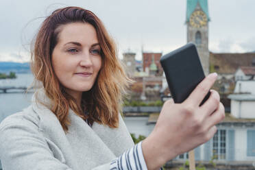Young woman taking smartphone picture in the city, Zurich, Switzerland - FBAF00804