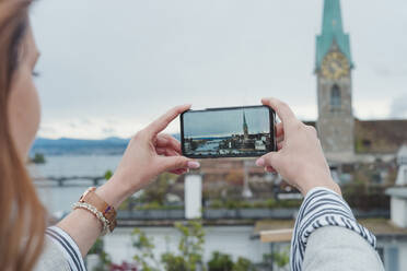 Junge Frau fotografiert mit ihrem Smartphone in der Stadt, Zürich, Schweiz - FBAF00805