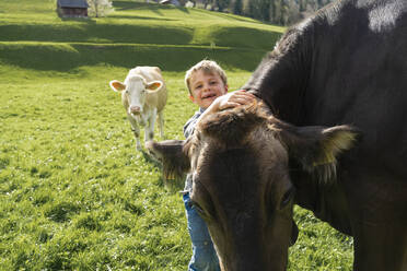 Glücklicher Junge mit Kuh auf der Weide - FBAF00822