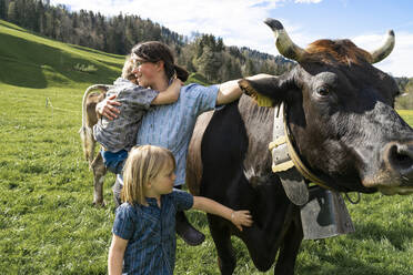 Mother with two children on cow pasture - FBAF00828