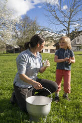 Mutter und Tochter mit frischer Milch in einem Eimer auf der Weide - FBAF00850