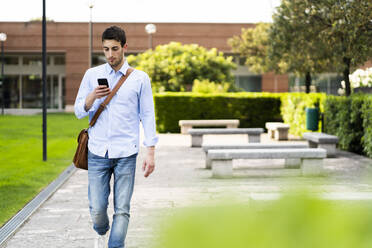 Junger Mann mit Smartphone in der Stadt - GIOF06507