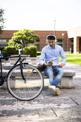 Young man with bicycle using smartphone and listening music - GIOF06527