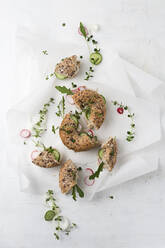 Bagels with butter, red radishes, cucumber, onions and herbs on parchment paper - MYF02116