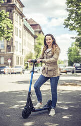 Portrait of smiling woman with E-Scooter - BFRF02023