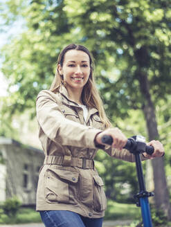 Portrait of smiling woman with E-Scooter - BFRF02024
