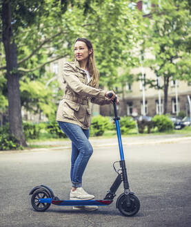 Portrait of smiling woman with E-Scooter - BFRF02025