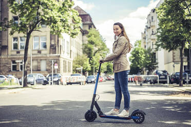 Portrait of smiling woman with E-Scooter in the city - BFRF02028