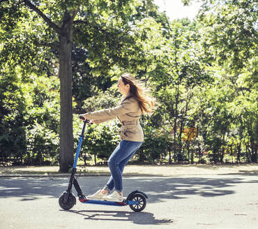 Smiling woman riding E-Scooter - BFRF02030